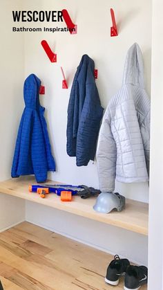 there are several coats and shoes on the shelf in this room, all lined up against the wall