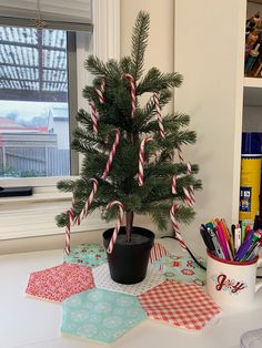 a small christmas tree sitting on top of a table next to a potted plant