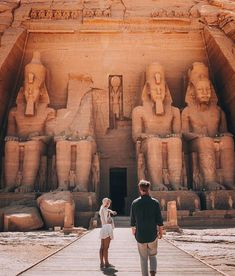 a man and woman standing in front of an egyptian temple