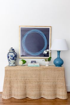 a blue and white vase sitting on top of a table next to a framed painting