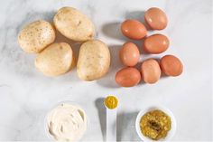 eggs, mayonnaise and other ingredients on a white counter top with a spoon