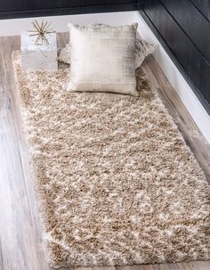 a white rug on top of a wooden floor next to a pillow and other items