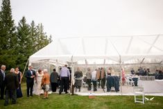 a group of people standing under a white tent