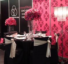 a table set up with black and white linens, pink flowers and crystal vases