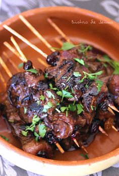 a bowl filled with meat and veggies on skewered toothpicks