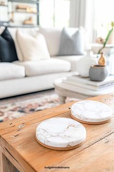 two white plates sitting on top of a wooden table in front of a living room couch