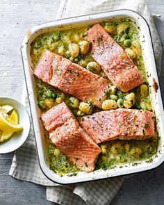 salmon and potatoes in a casserole dish with lemon wedges