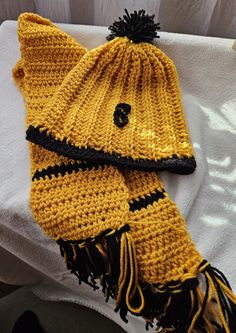 a yellow knitted hat and scarf laying on top of a white towel