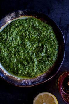 a pan filled with spinach sauce next to sliced lemons