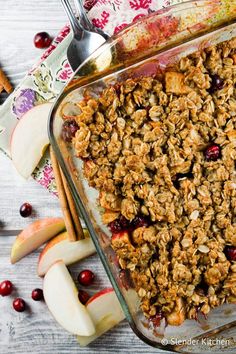 a glass dish filled with granola next to apples and cinnamon sticks