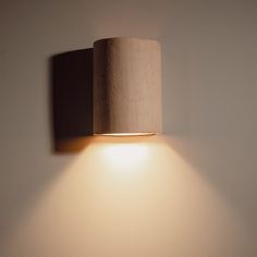 a wall light that is on the side of a wall with a white lamp underneath it