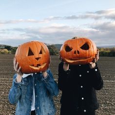 two children holding pumpkins with faces carved into them