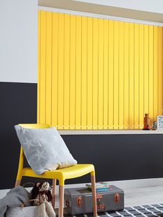 a yellow chair sitting in front of a window next to a stuffed animal on a rug