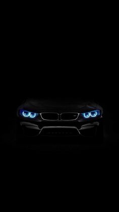 the front end of a black bmw car with blue lights on it's headlights