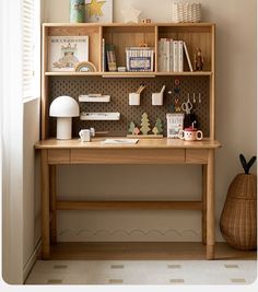 a wooden desk sitting under a window next to a shelf filled with books and other items