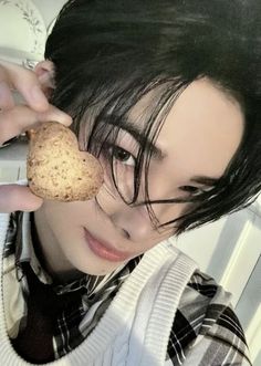 a person holding a cookie in front of their face with one hand and the other eye closed