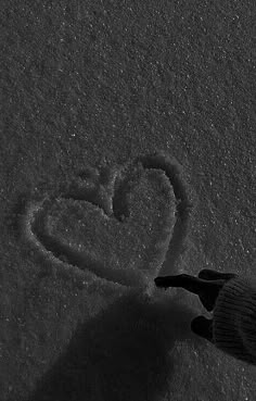 a person is writing in the snow with a heart drawn on it's side