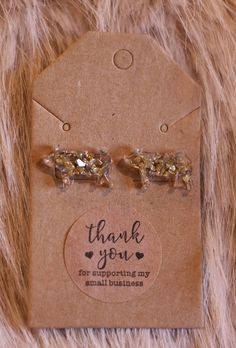 a pair of gold colored earrings on top of a brown tag that says thank you for supporting my small businesses