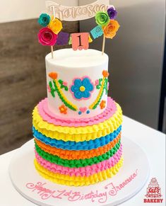 a birthday cake decorated with multicolored ruffles and a happy 1st birthday sign