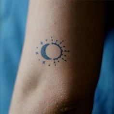 a tattoo on the arm of a person with a sun and moon in the background