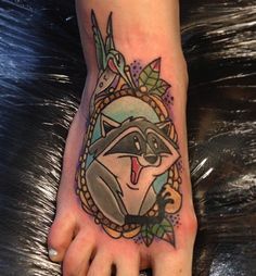 a raccoon tattoo on the foot of a person