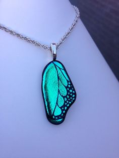 a necklace with a blue butterfly wing on it's back end and a silver chain around the neck