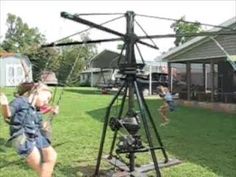 children are playing in the yard with a helicopter on a tripod and another child is standing next to it