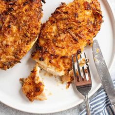 two pieces of chicken on a plate with a fork