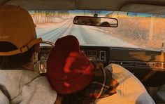 two people in the back seat of a car driving down a road with snow on the ground