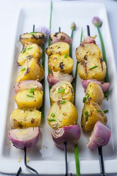 grilled lemon - garlic potato kabobs on a white platter with green onions