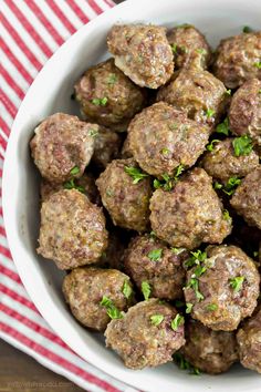 a white bowl filled with meatballs on top of a red and white checkered table cloth