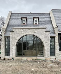 an old brick house with large windows and stone roof