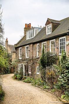 an old brick house with white windows and lots of greenery