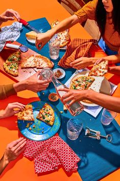 a group of people sitting around a table eating pizza