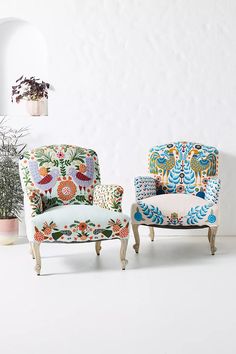 two chairs sitting next to each other in front of a wall with potted plants