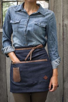 a woman is wearing an apron and has her hands in her pockets as she poses for the camera