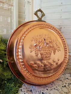 an ornate gold plate sitting on top of a table next to a potted plant