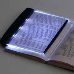 an open book sitting on top of a table next to a lit up light source