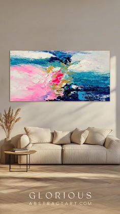 an abstract painting hangs on the wall above a couch in a living room with white walls