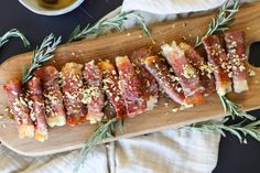 sliced up meat on a wooden cutting board next to a cup of tea and napkin