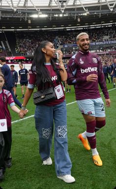 a man and woman walking across a soccer field