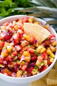 a white bowl filled with fruit salsa and a tortilla chip on the side