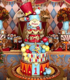 a multi - tiered circus themed birthday cake with balloons and decorations on the top