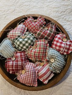 a wooden bowl filled with plaid pillows on top of a white tablecloth covered floor