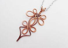 a necklace made out of copper wire on a silver chain with an intricate design in the middle