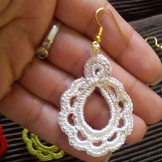 someone is holding some white crochet earrings