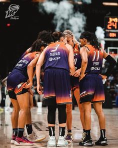 a group of women in purple and orange basketball uniforms huddle together