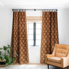 an orange chair sitting in front of a window next to a potted green plant