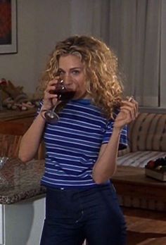 a woman standing in a living room holding a glass of wine