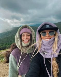 two women standing next to each other on top of a mountain